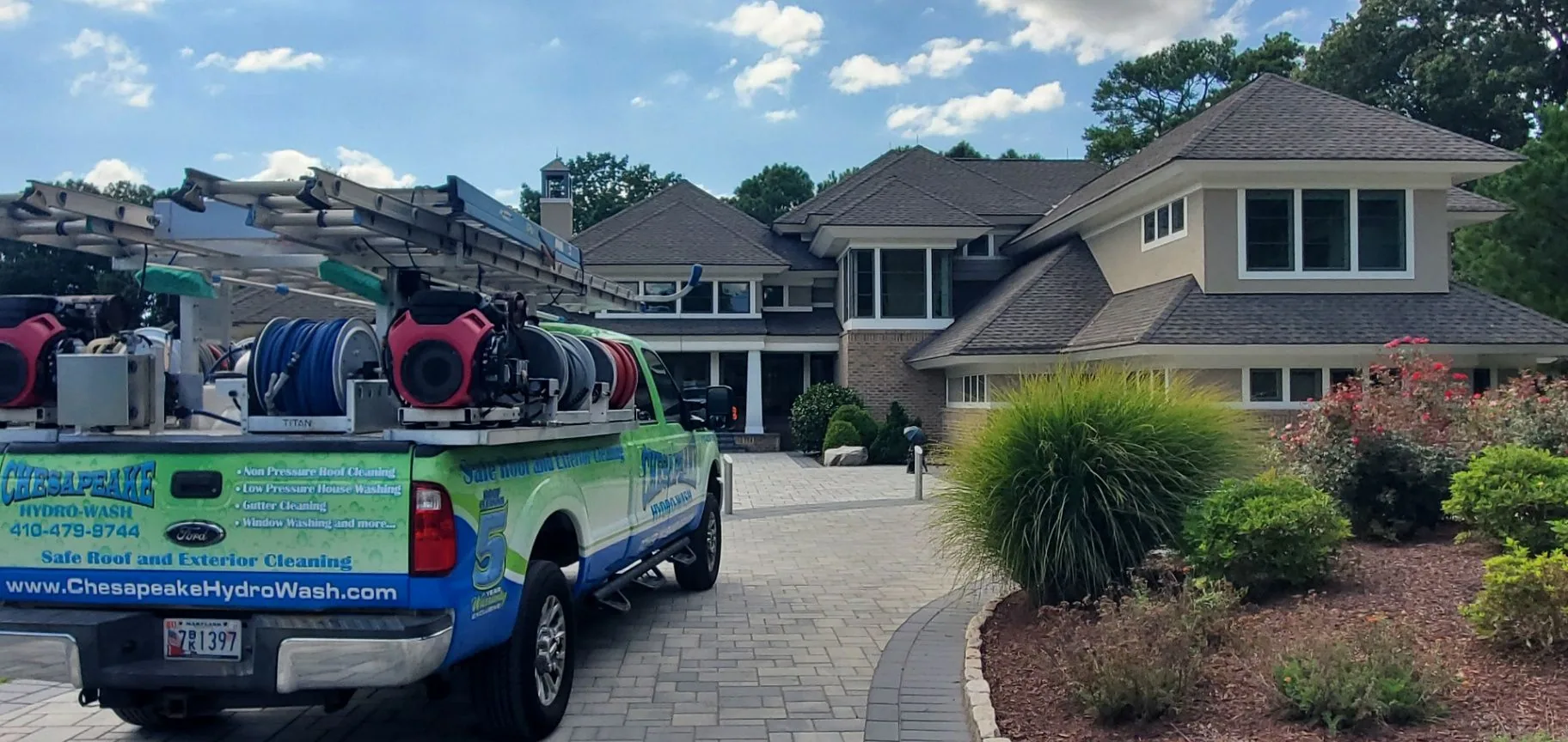 Chesapeake Hydro-Wash truck and roof-cleaning equipment outside a landscaped Maryland home